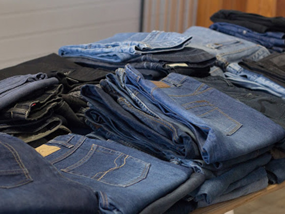 A folded pile of used denim trousers