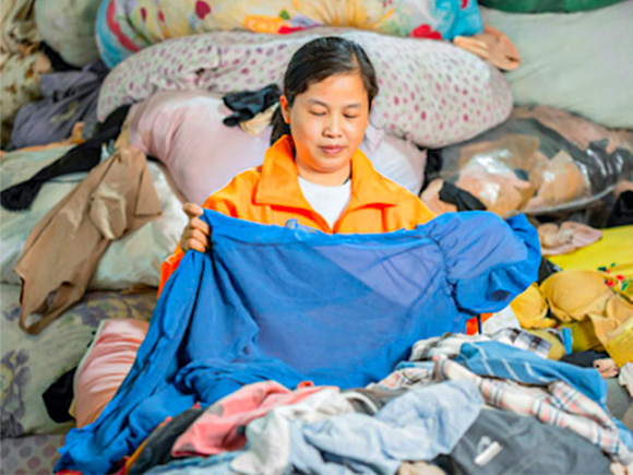 Woman inspecting second hand clothes at a warehouse