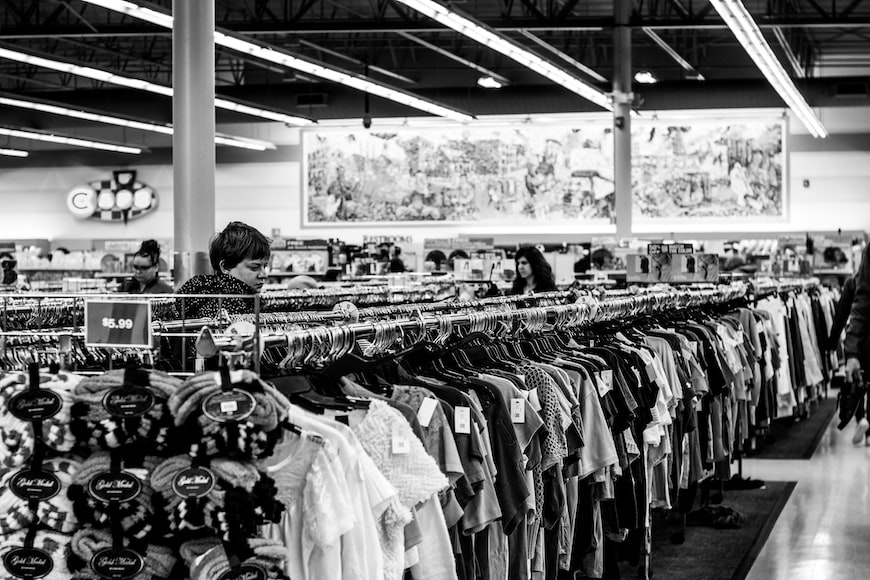 A black and white photo of a row of Second hand clothes.