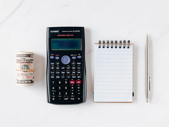 Composition of the calculator with paper money and notebook with pen