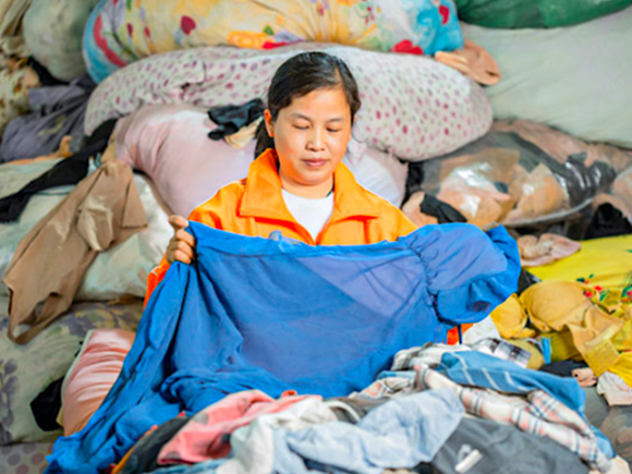 Woman inspecting second hand clothes at a warehouse