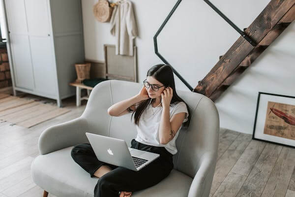 Woman using earphones and laptop at home