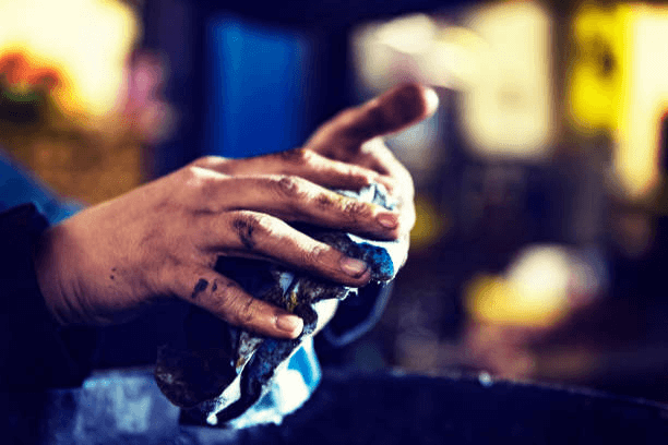a man wipes oily hands with rags