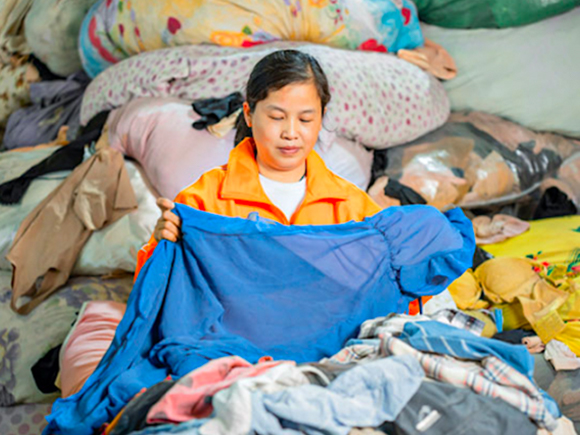 Woman inspecting second hand clothes at a warehouse