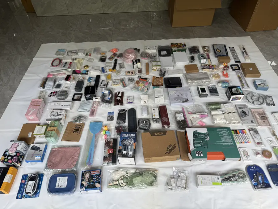 Second mixed wholesale stock lot spread out showing electronics, household items, tools, bags and accessories from the same carton